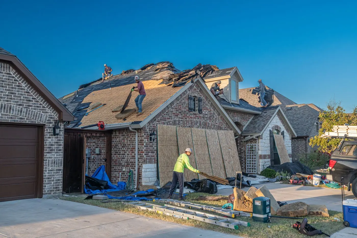 Dakreparatie aan een woonhuis met werkers op het dak